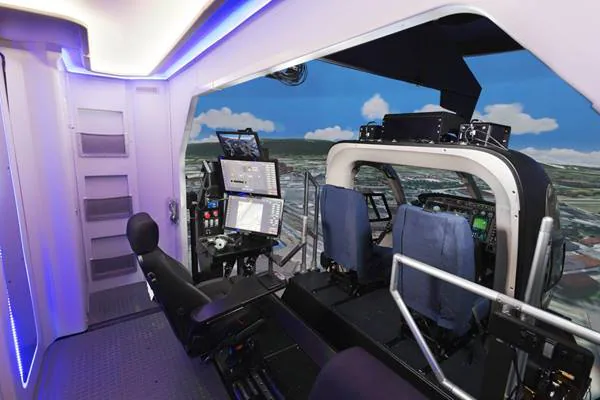Interior cockpit of a flight simulator with control panels and screens.