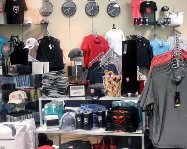 A display of merchandise including hats, shirts, and accessories in a retail store with wall clocks.