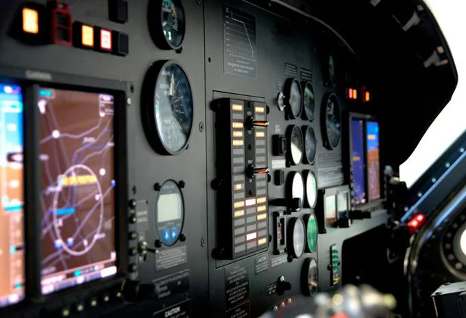 Cockpit control panel featuring various instruments, screens, and navigation displays.