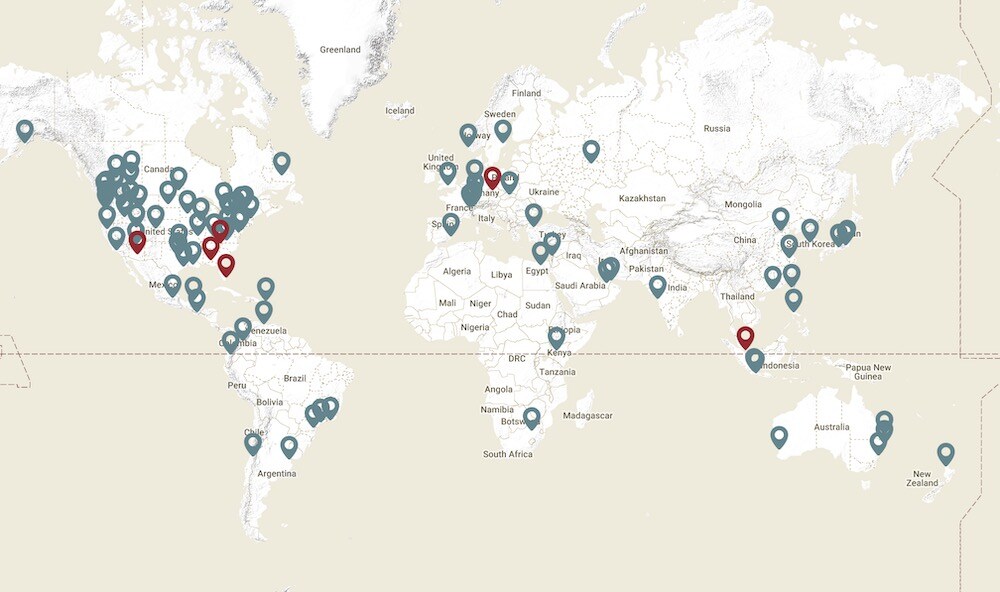 World map with multiple locations marked by blue and red pins, indicating various sites.