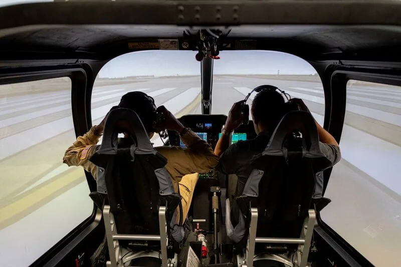 Two pilots in a flight simulator, focused on takeoff on a runway.