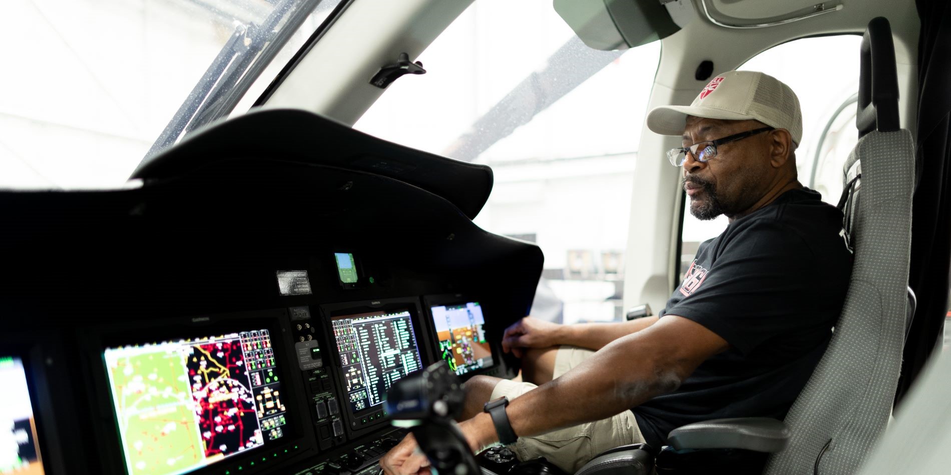 Pilot seated at a cockpit, interacting with digital flight displays and controls.