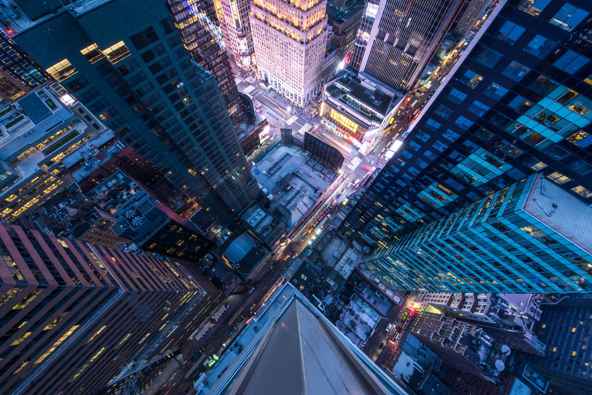 Aerial view of illuminated skyscrapers and streets in a bustling city at twilight.