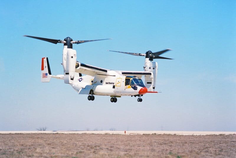 Military tiltrotor aircraft airborne, with two large rotor blades and a distinct fuselage design.