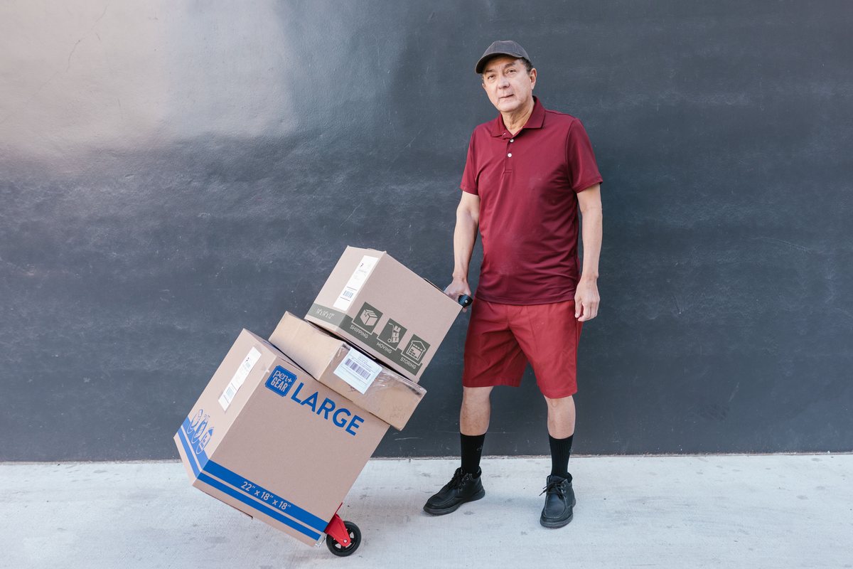 A warehouse worker standing beside a hand truck loaded with boxes