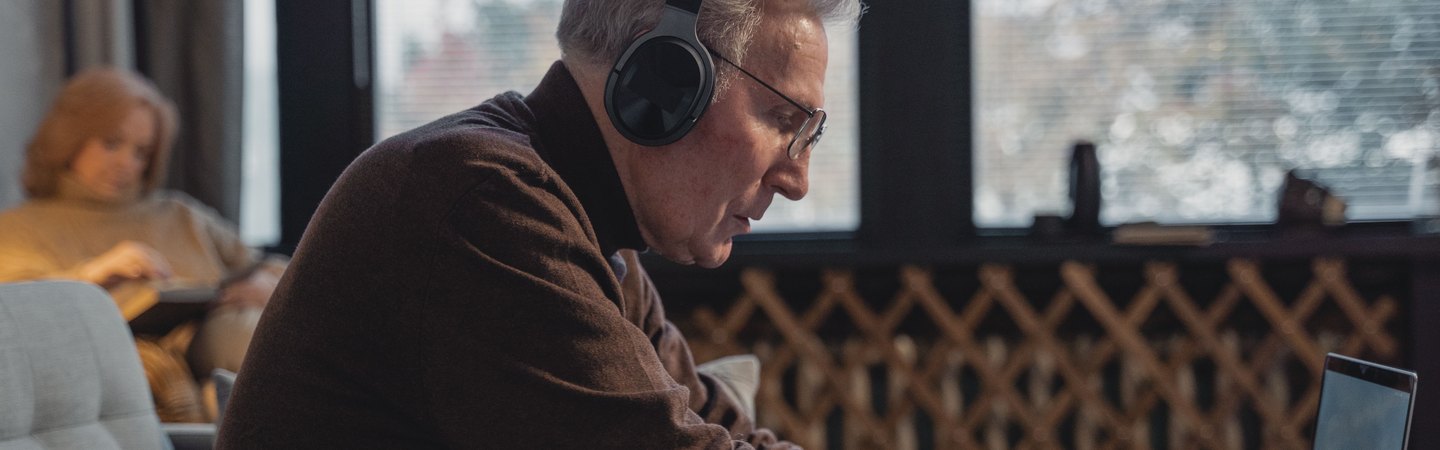 A remote support representative wearing headphones and working on a laptop at home