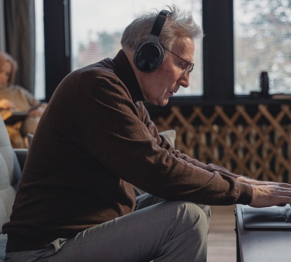 A remote support representative wearing headphones and working on a laptop at home