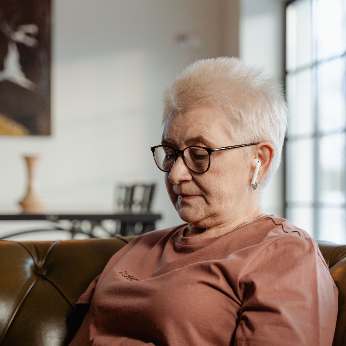 A support representative working from a couch with a laptop and earbuds