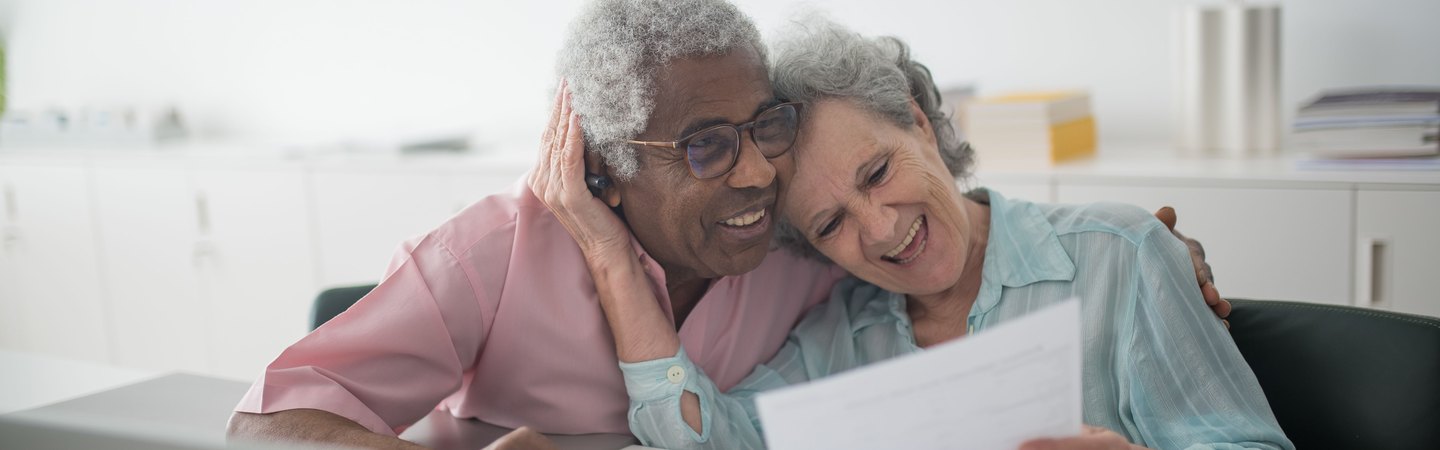 Two people smiling as they read a document together at a laptop