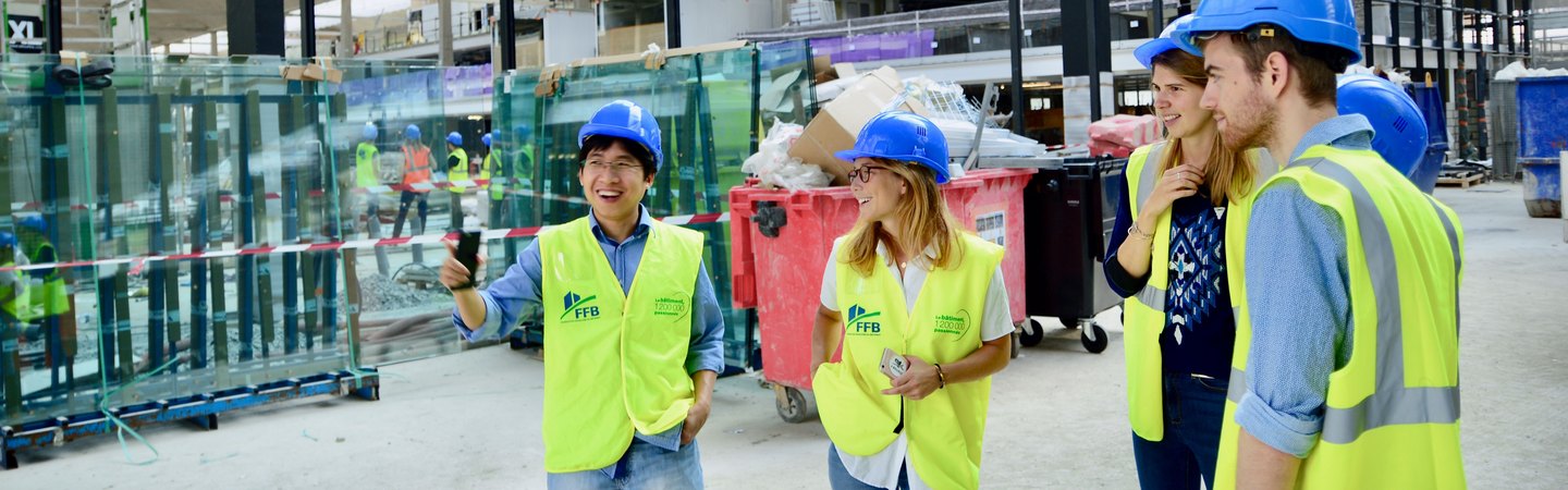 A group of workers in hard hats and hi-vis vests talking on a construction site