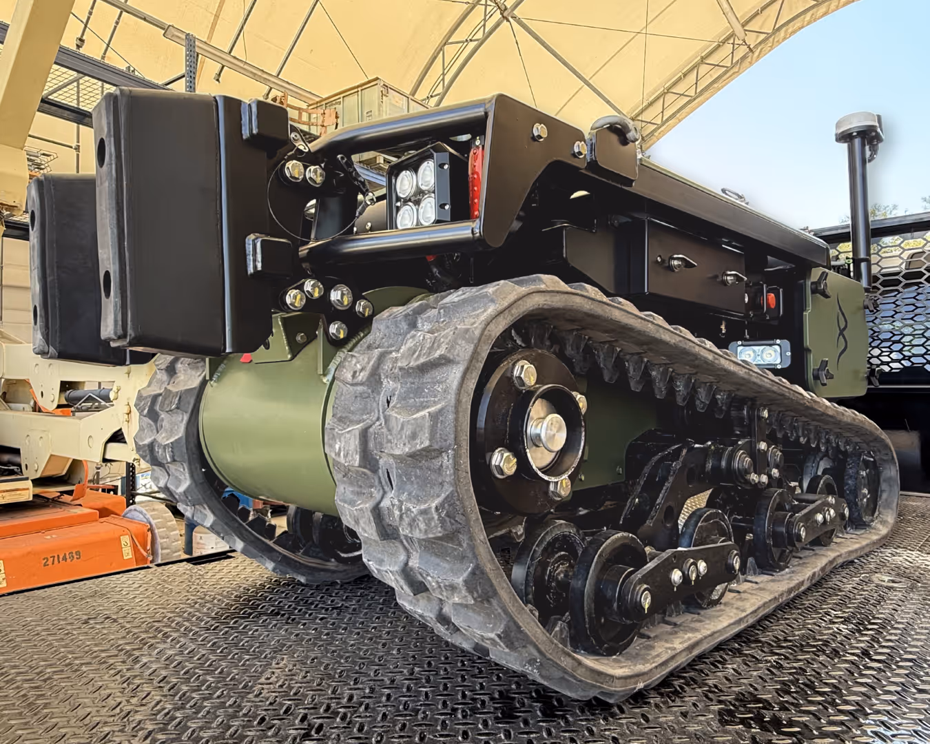 Close-up of a rugged tracked robotic vehicle under a canopy structure.