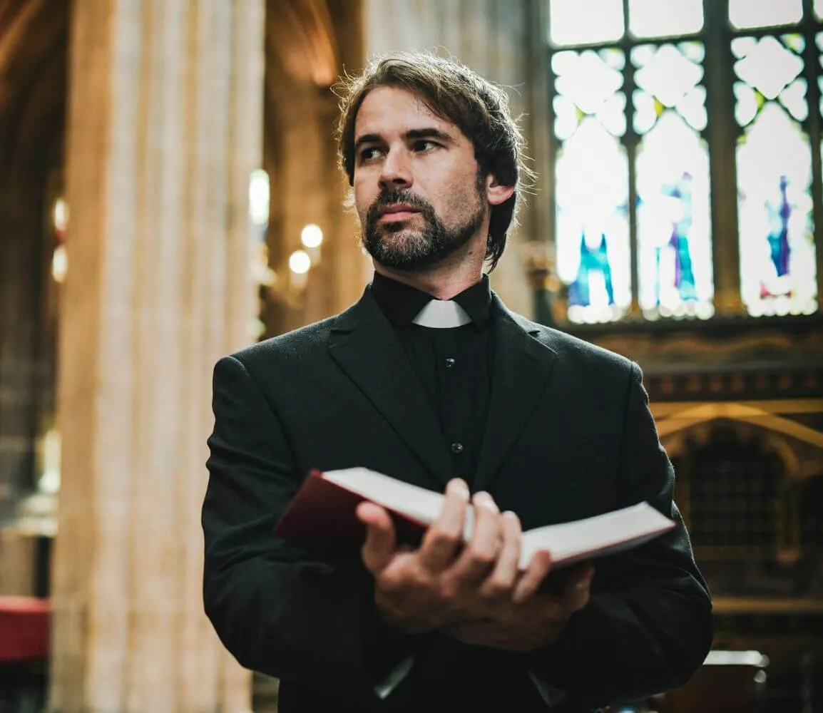 a man in a priest's outfit holding a bible