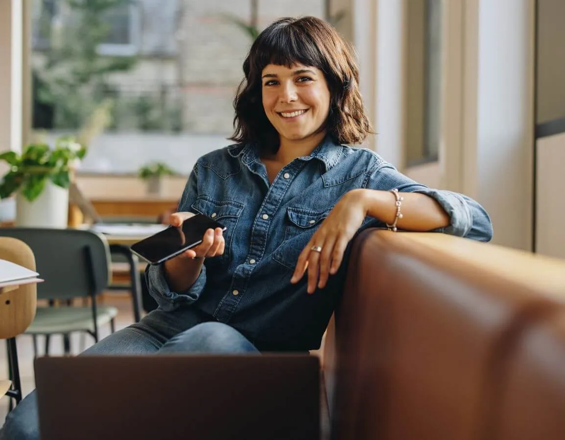 a woman sitting in a chair holding a cell phone