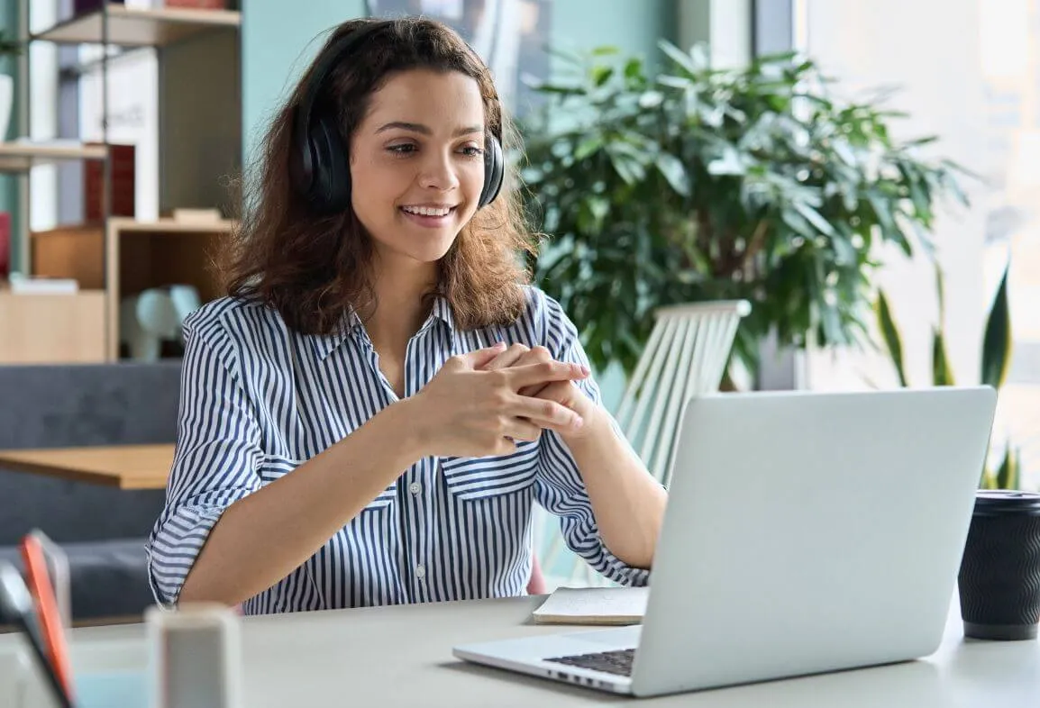 a woman sitting at a table with a laptop and headphones