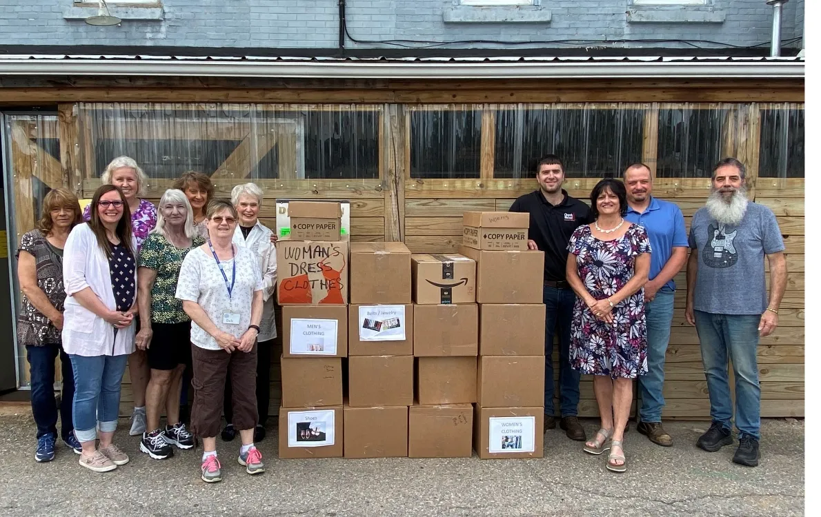 a group of people standing next to a pile of boxes