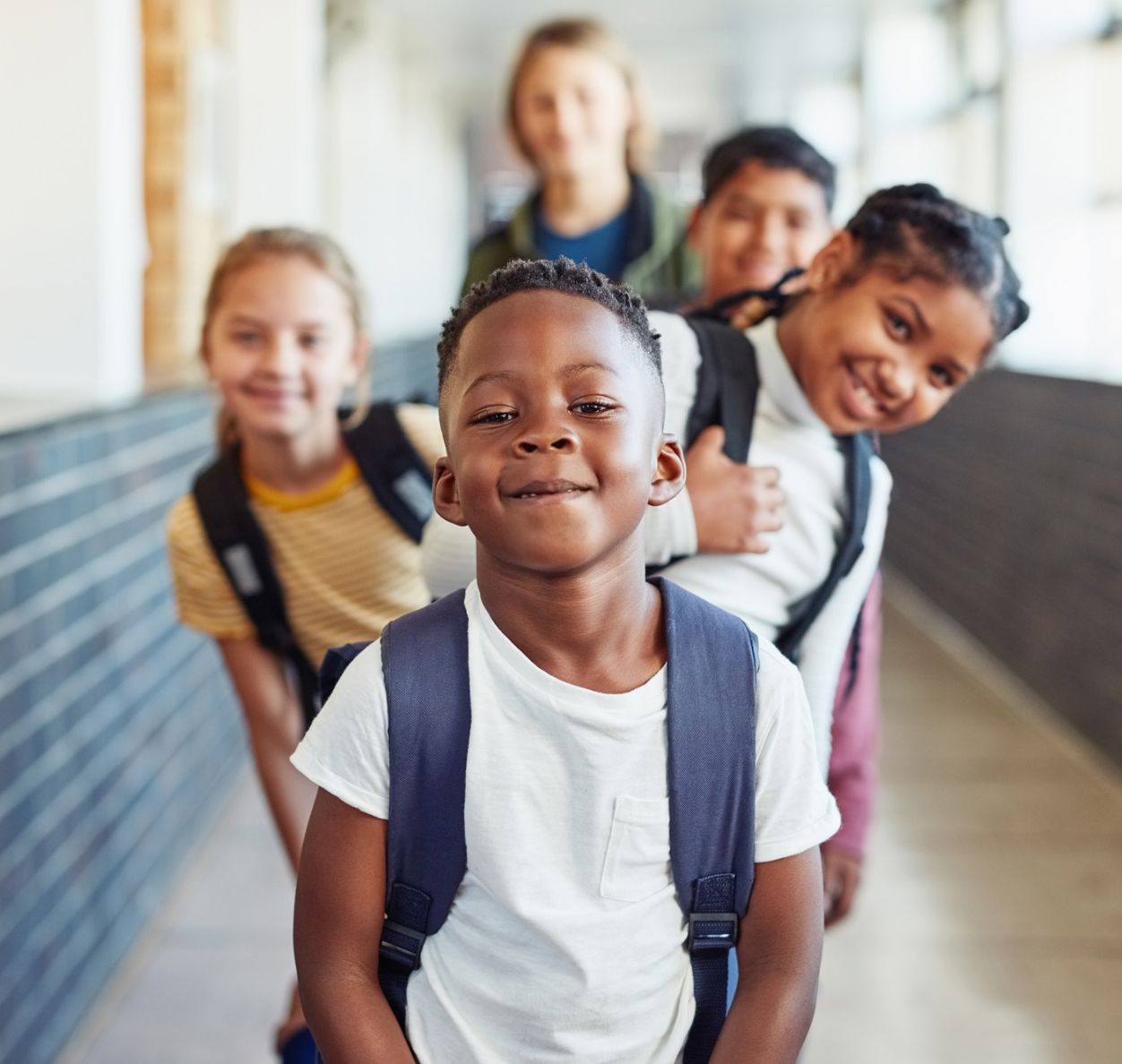 kids in line in a school hallway wearing backpacks