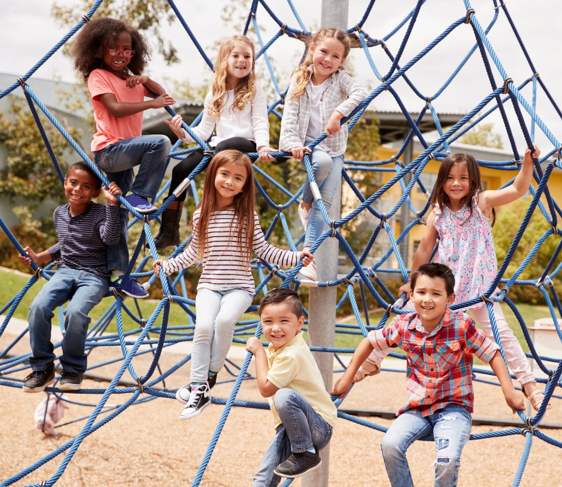 a group of kids on a rope jungle gym at a school playground