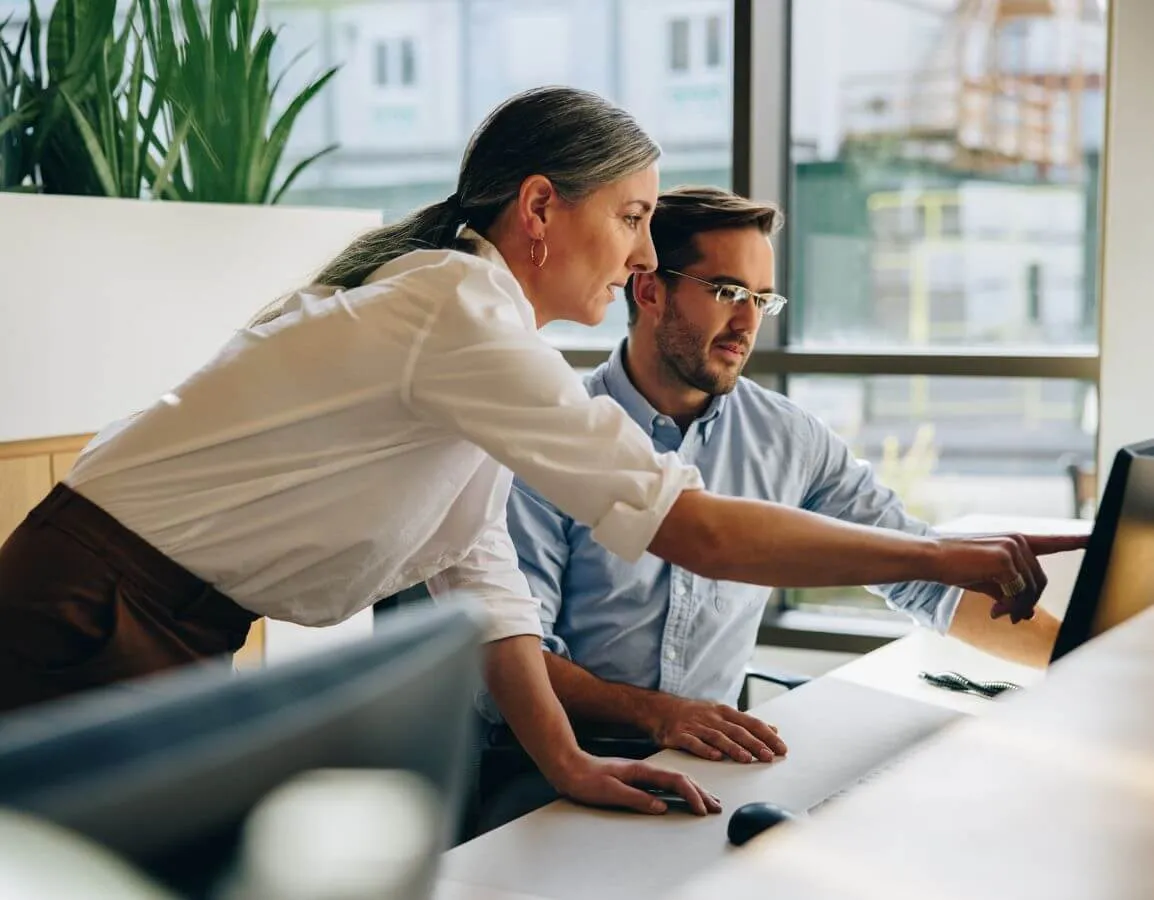 a man and a woman are looking at a computer screen