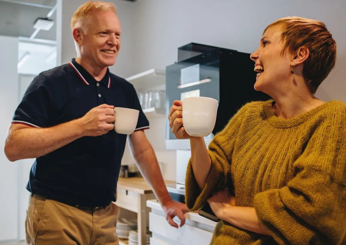 a man standing next to a woman holding a cup of coffee
