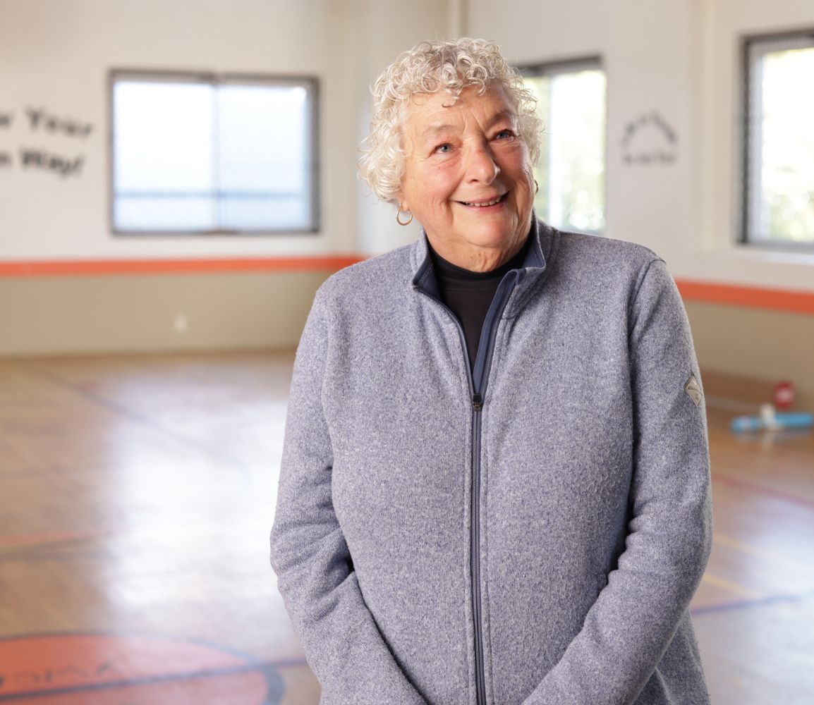 a woman standing in a basketball gym smiling