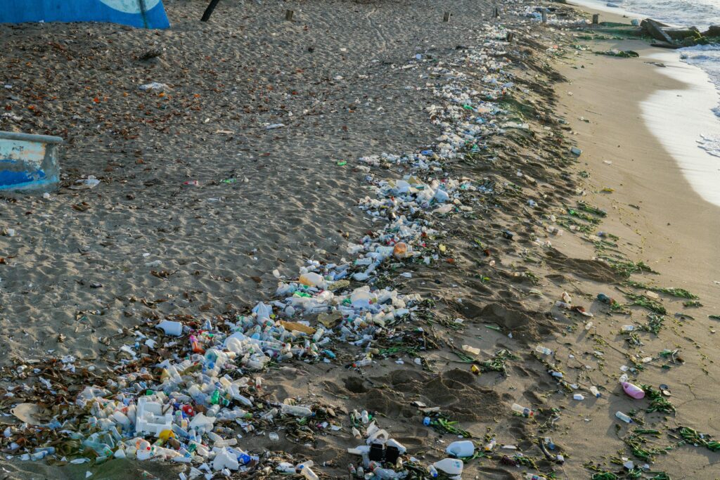 Image of a polluted beach. The beach is littered with plastic bottles and other plastic materials. 