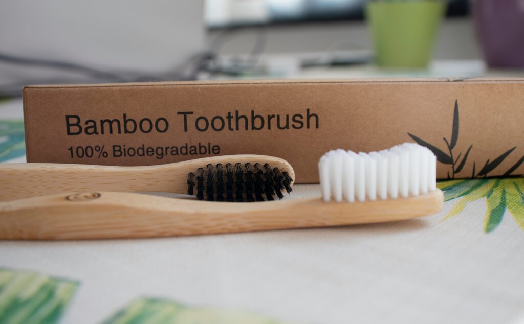 An image of a toothbrush made out of bamboo. There are two toothbrushes one with black bristles and one with white bristles.