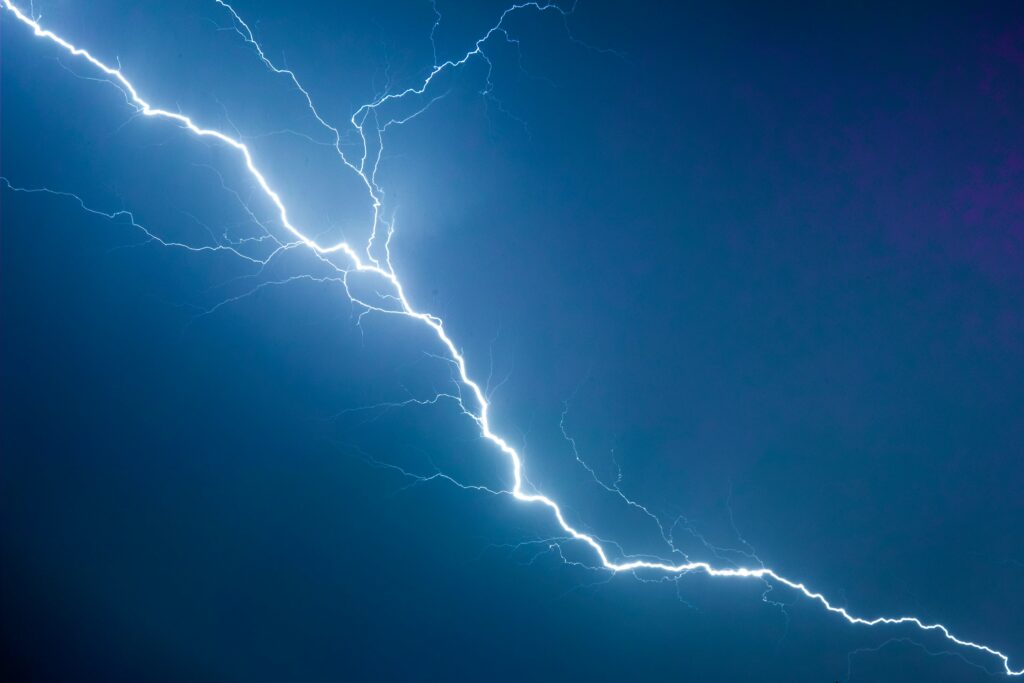 An image of a white lighting bolt in a dark blue sky background. 