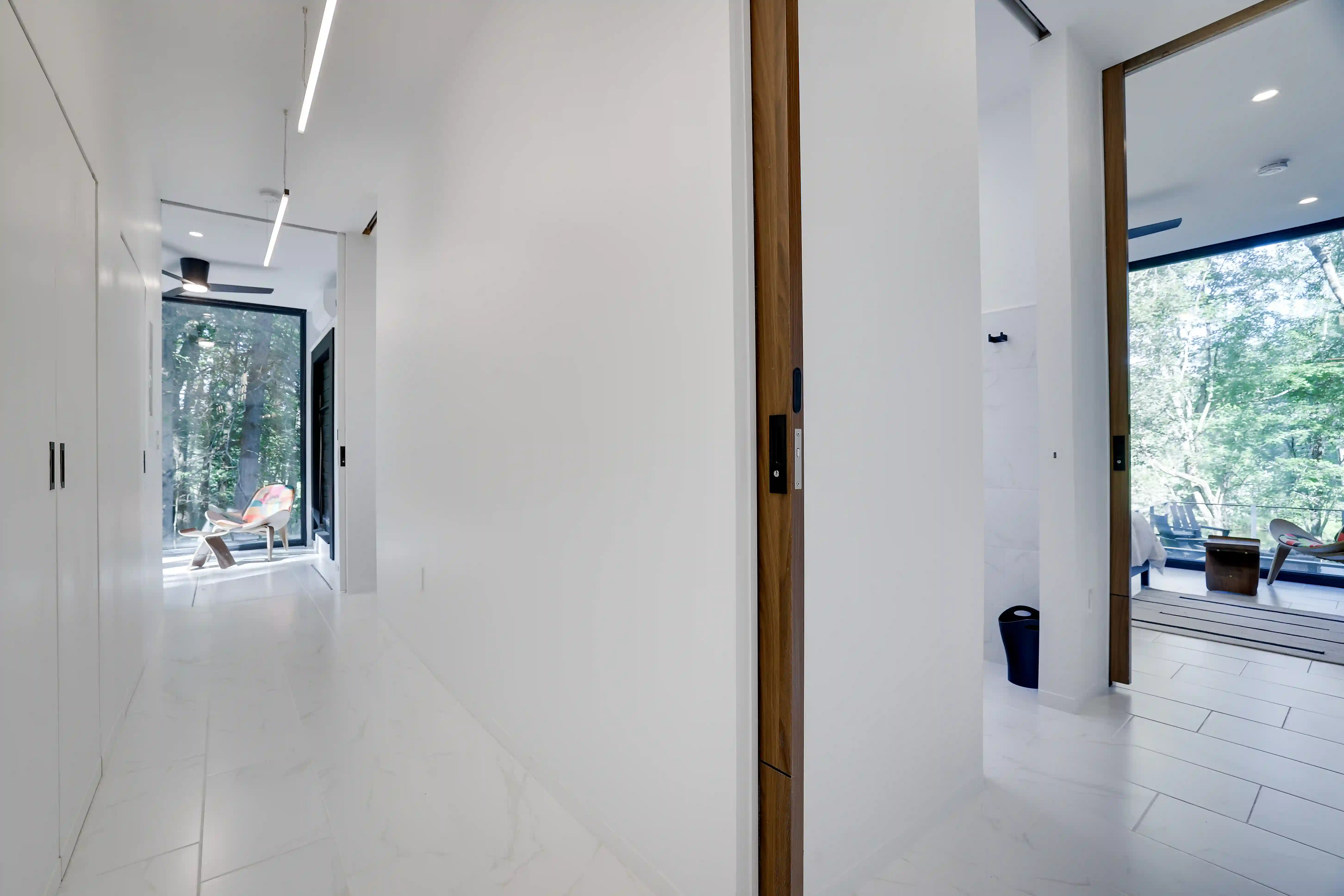 White hallway with a walnut pocket door, built-in closets, and a glass door opening to the deck.