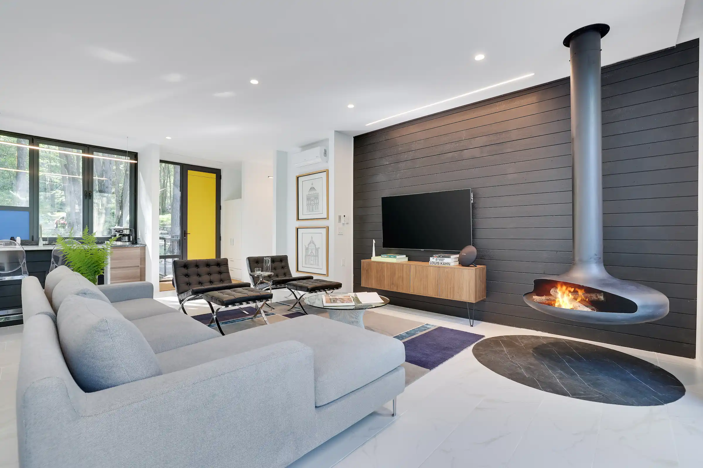 Lit suspended fireplace beside a gray sectional sofa against a charred wood accent wall in the living room.
