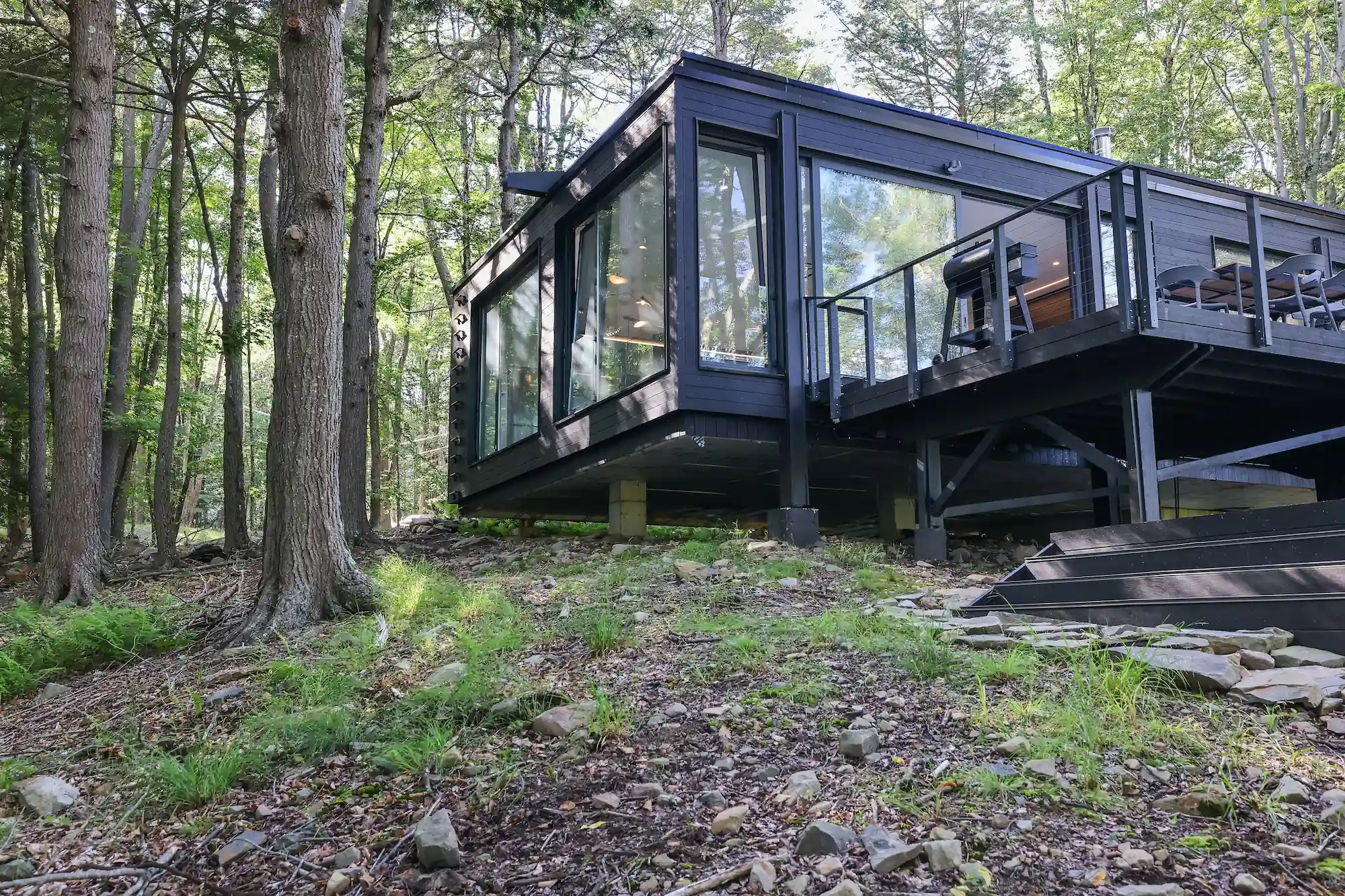 Camp Double Oak's charred wood exterior elevated on steel piers, anchored lightly to the forest floor.
