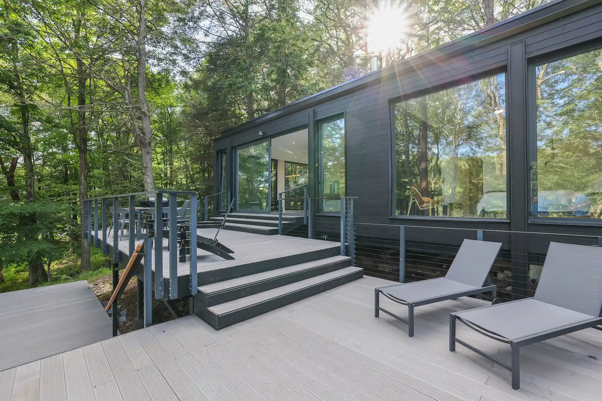 Cantilevered deck with lounge chairs extending from the glass pavilion into the treetops.