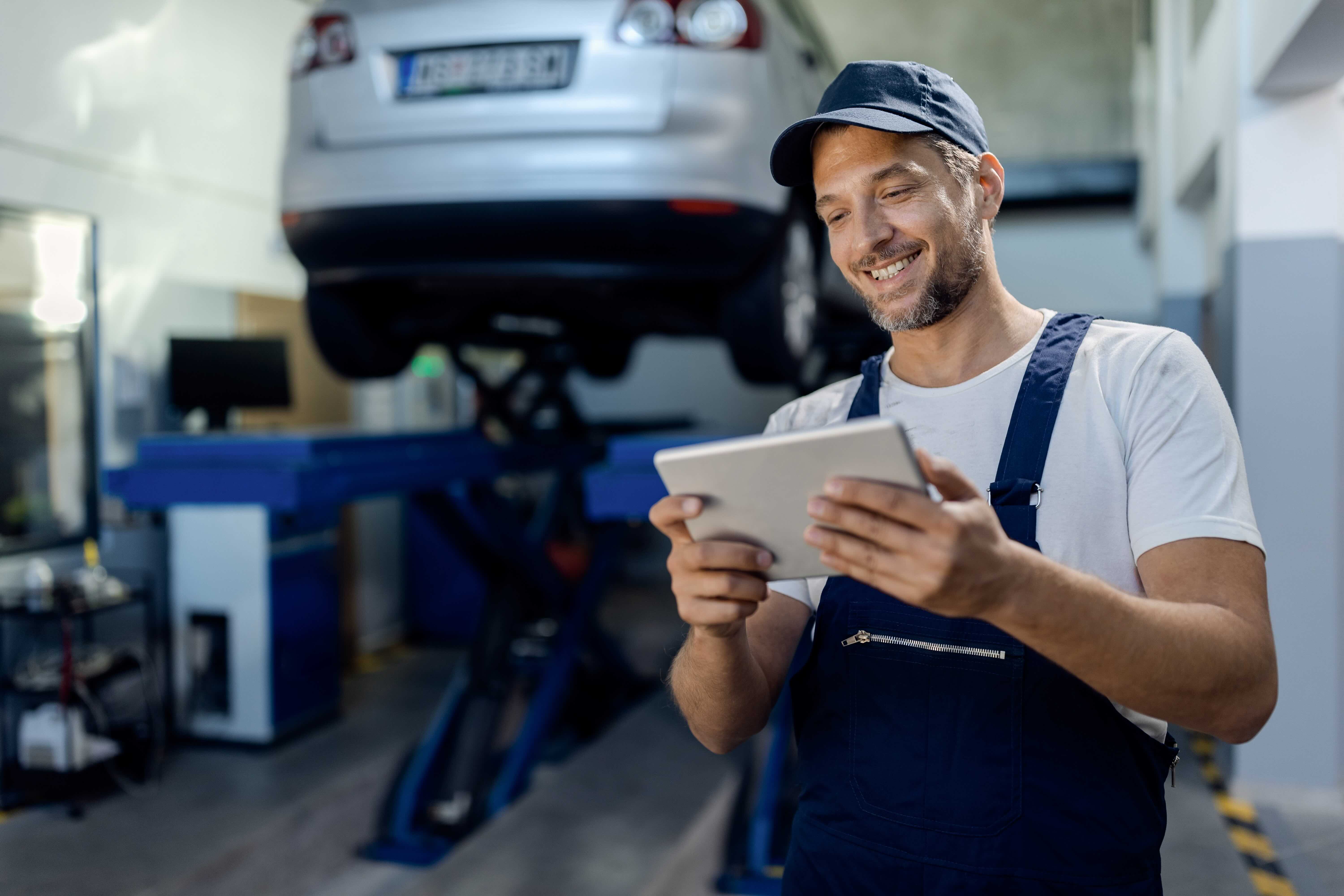 Auto repair shop owner checking his business reviews on a tablet in the workshop