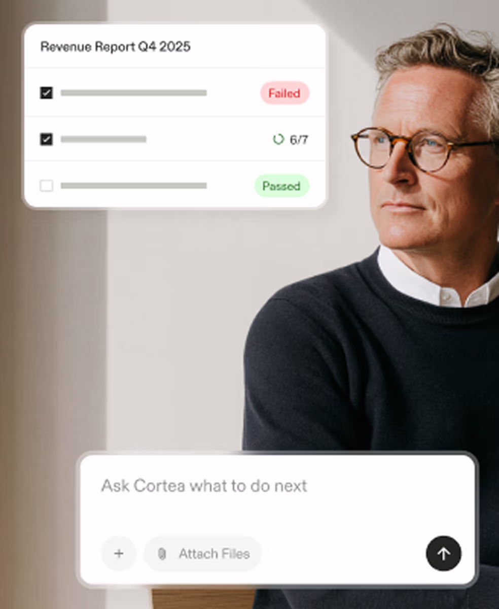 Man with glasses looks to the side with revenue report and chat box about tasks on screen.