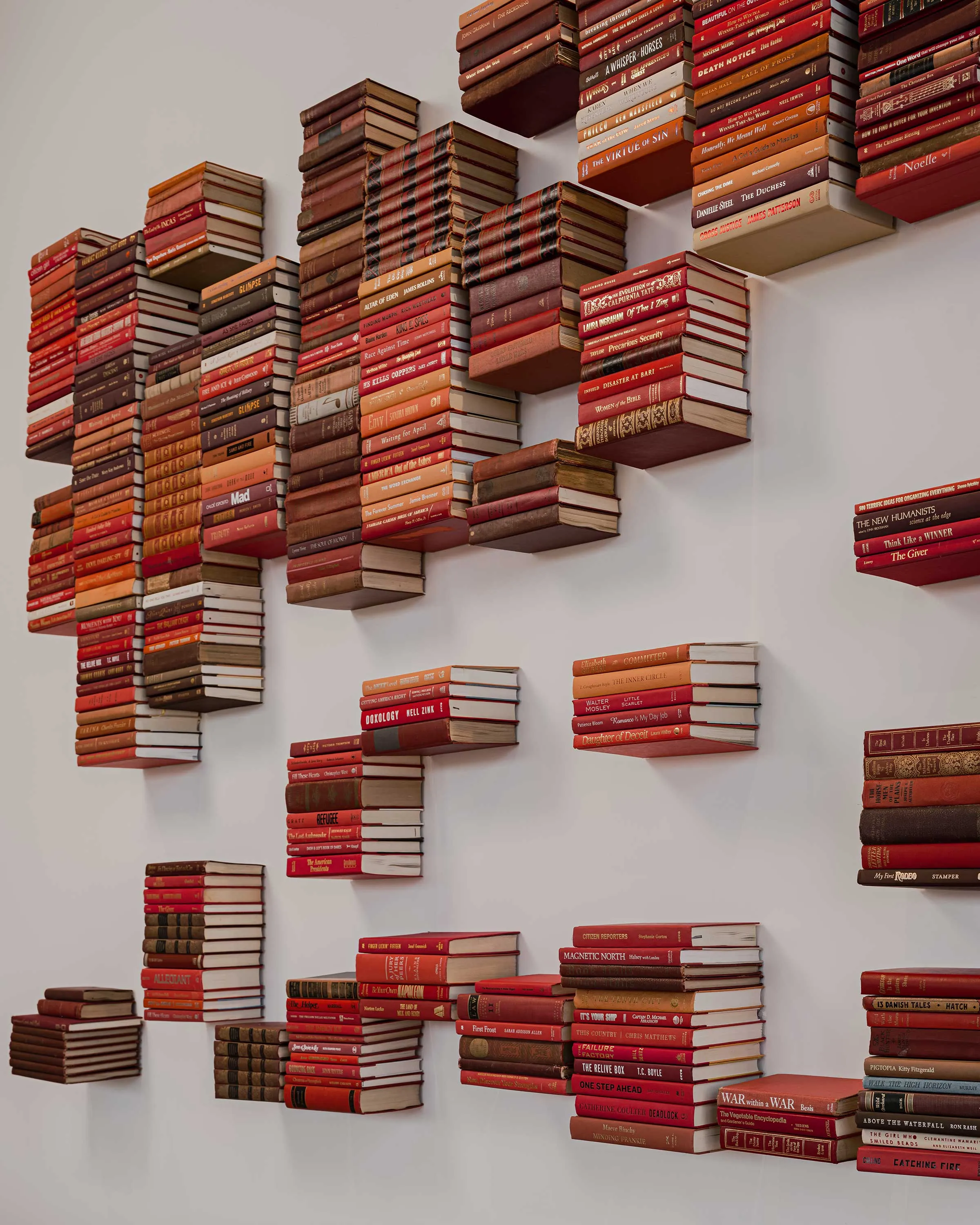 600 vintage books arranged in layered red shades forming desert canyon striation, Canyon Archive Phoenix