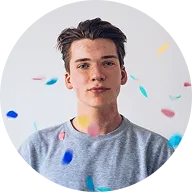Portrait of a young man with dark hair wearing a gray shirt, surrounded by colorful confetti.