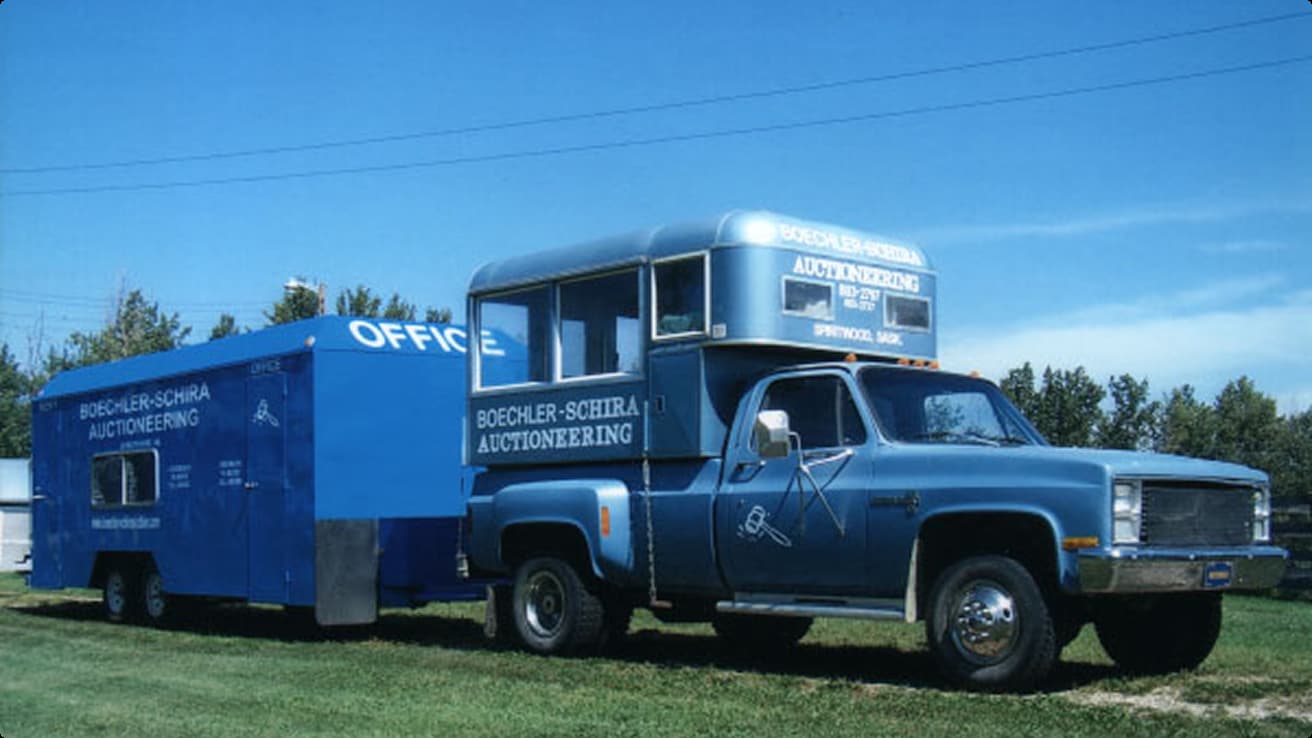 A blue truck parked in a grassy field.