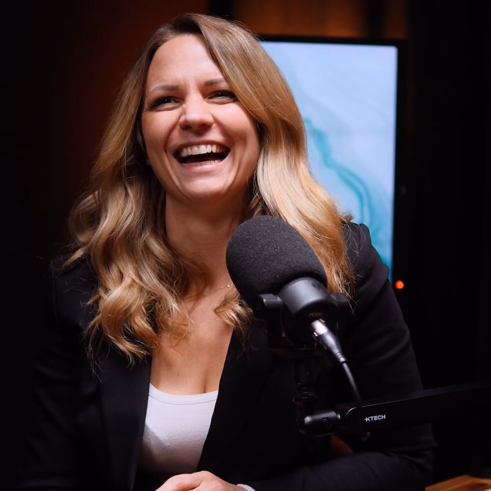 Lächelnde Frau spricht in ein Podcast-Mikrofon in einem Studio.