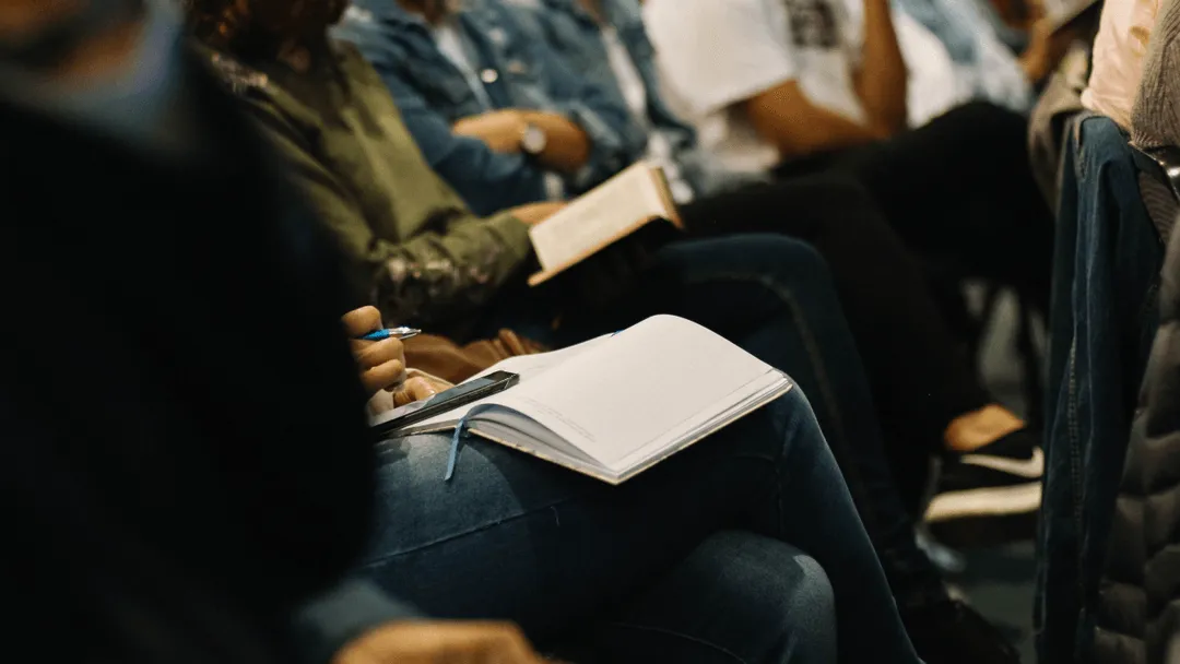 Close-up of people taking notes and reading books during a lecture or seminar.