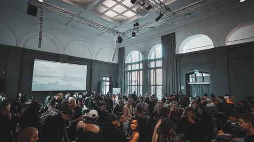 A bustling event hall filled with people networking and engaging with various booths and displays.
