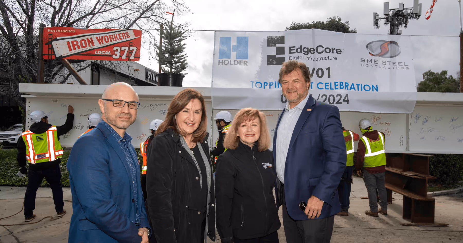 Four people posing at a data center topping-out ceremony