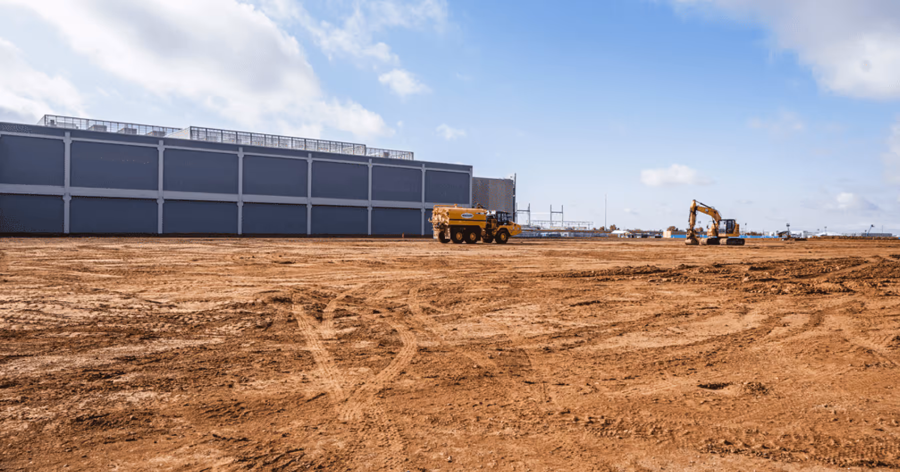 A data center building under construction with heavy equipment on the surrounding site