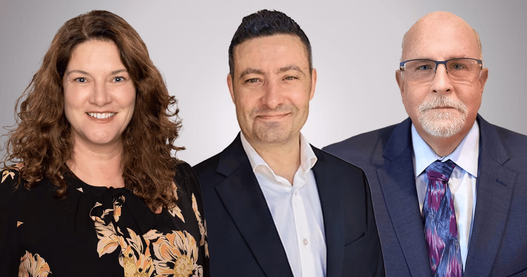 Three professionals smiling side by side against a light grey background