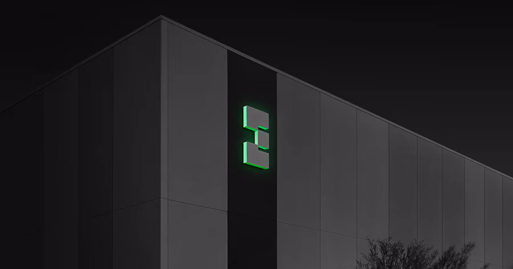 Data center building exterior at night with an illuminated green EdgeCore logo