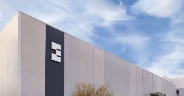 Exterior of a data center building with a large logo on the facade under a blue sky