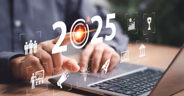 Person using a laptop with a holographic 2025 display and business icons floating above the keyboard