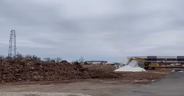 A construction site with earthmoving equipment and a partially built building under a grey sky