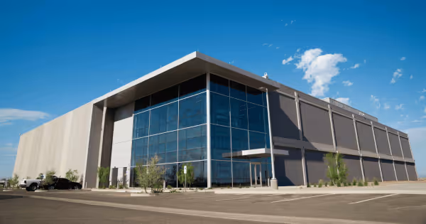 Exterior of a large data center building under a blue sky with cars in the parking lot