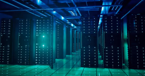 Rows of illuminated server racks in a dark teal-lit data center corridor