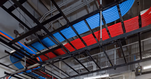 Interior of a data center with red and blue overhead cable management trays