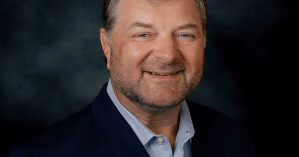 Headshot of Bill Jabjiniak against a dark background